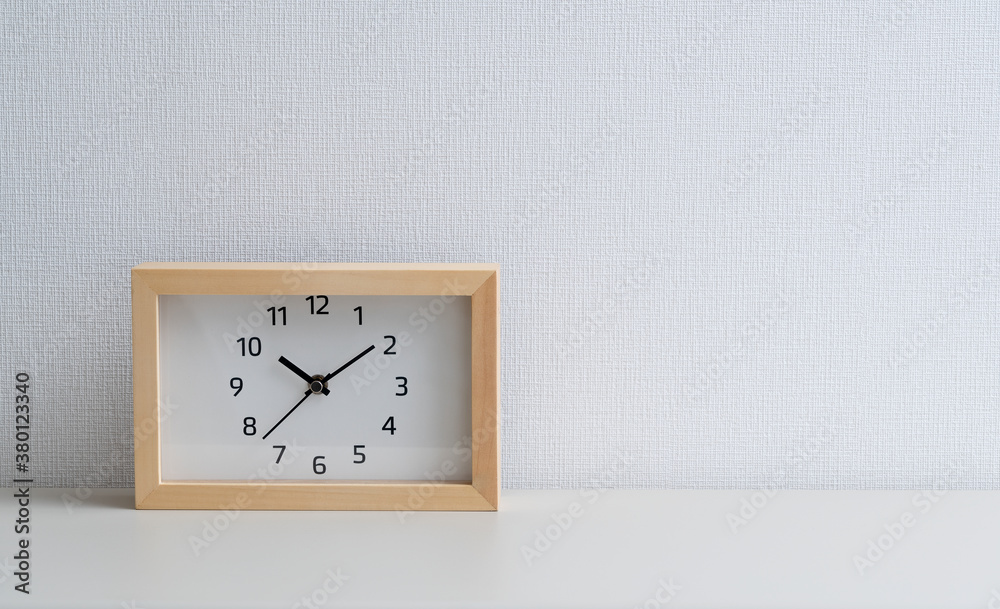 A square clock in front of a white wall