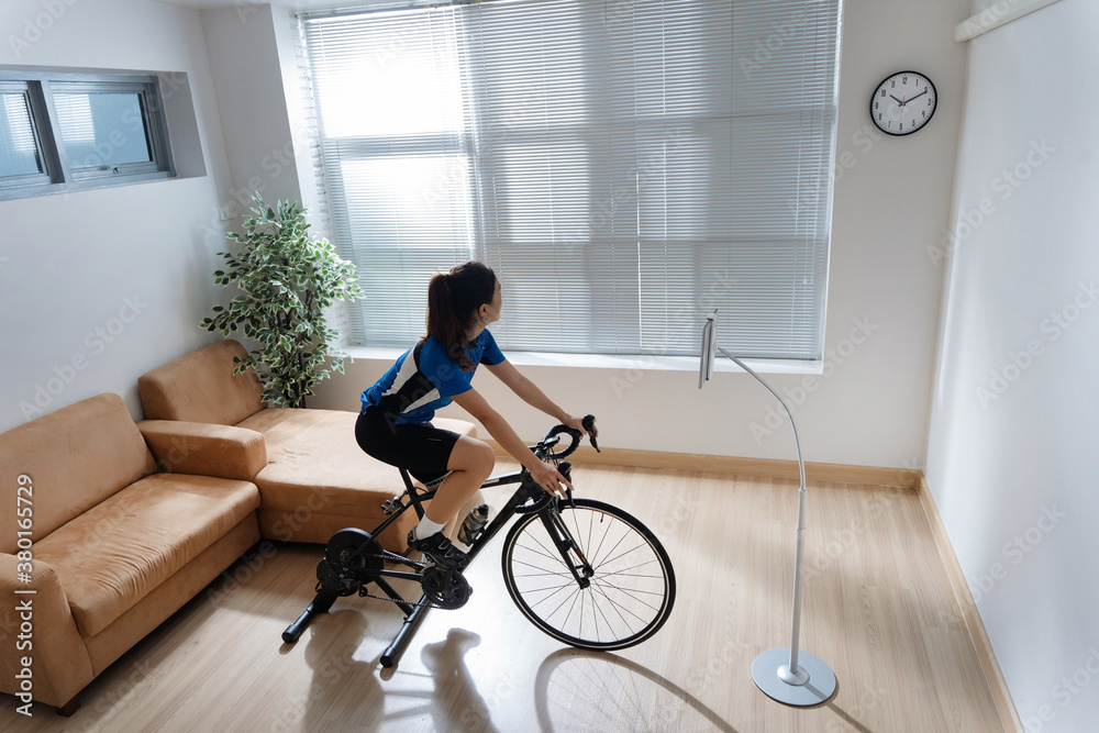 Asian woman exercising, she bicycles indoors. During the bad weather