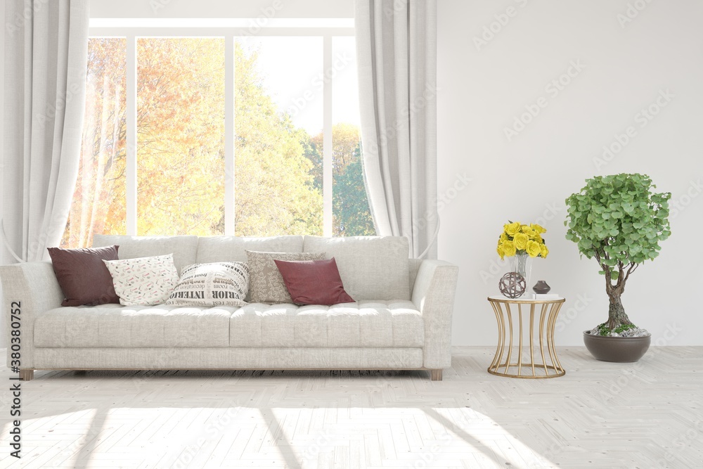 Stylish room in white color with sofa and autumn landscape in window. Scandinavian interior design. 