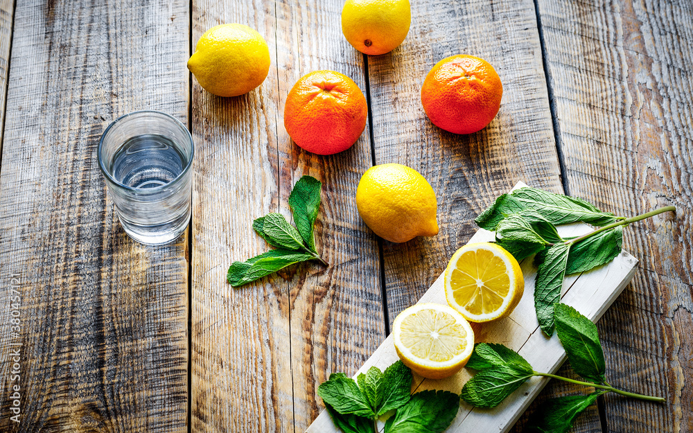 glass with ice and lemons, oranges, mint on wooden table