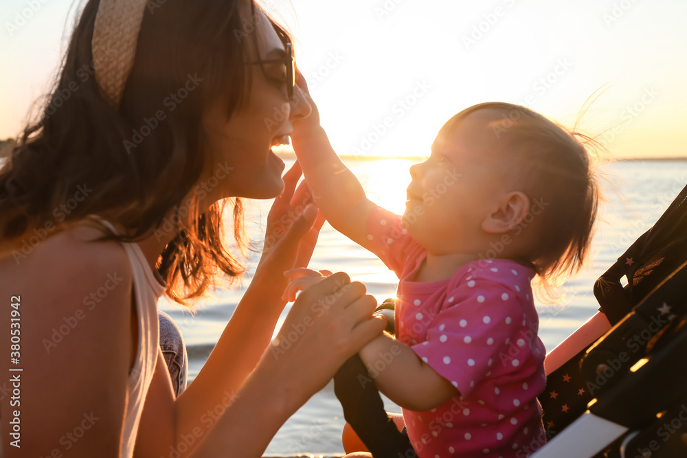 Woman and her cute baby in stroller near river