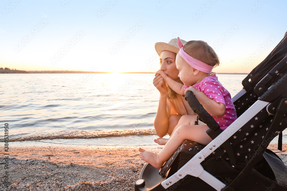 Woman and her cute baby in stroller near river