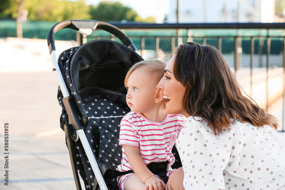 Woman and her cute baby in stroller outdoors