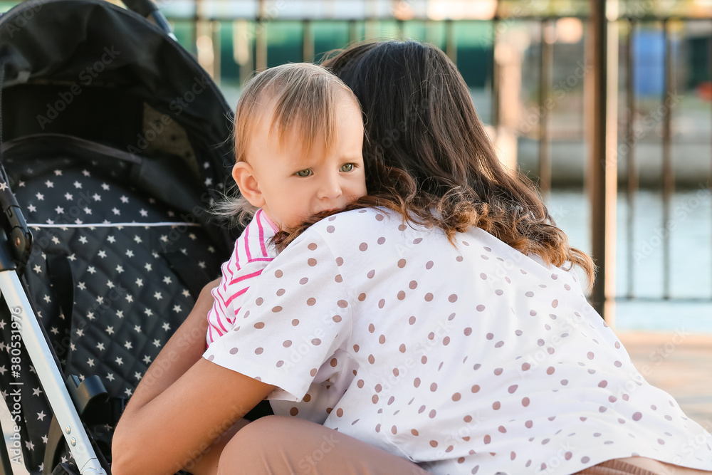 Woman and her cute baby in stroller outdoors