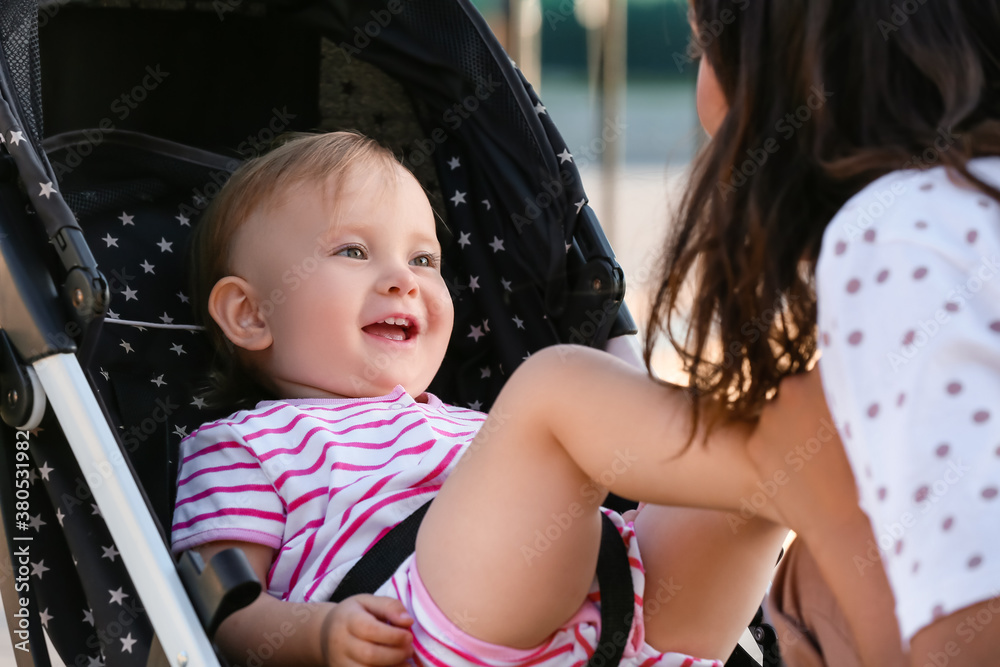 Woman and her cute baby in stroller outdoors