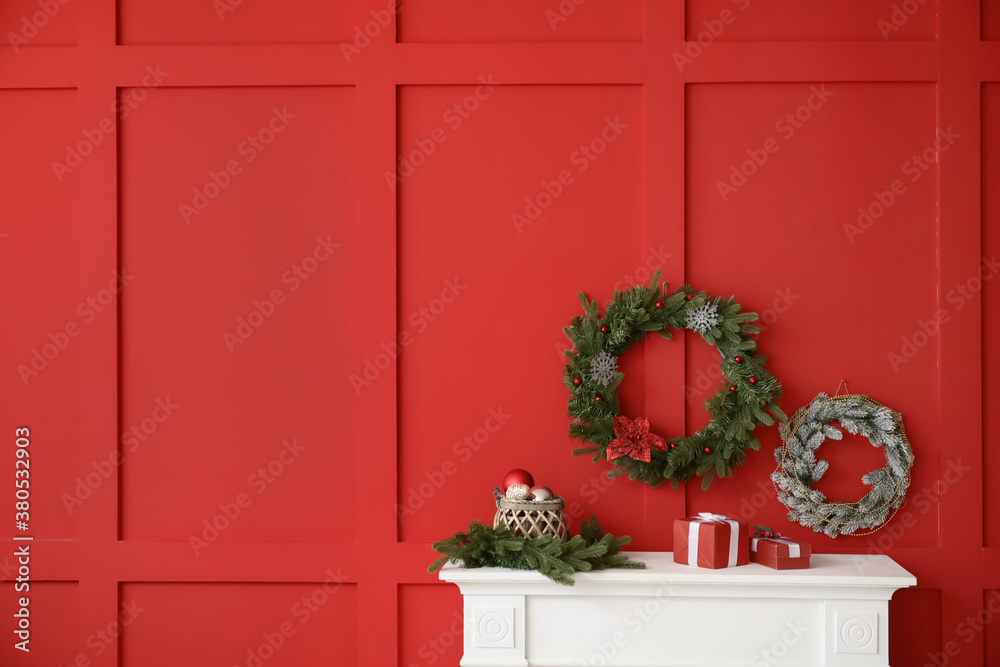 Beautiful Christmas wreaths hanging on wall near fireplace in room