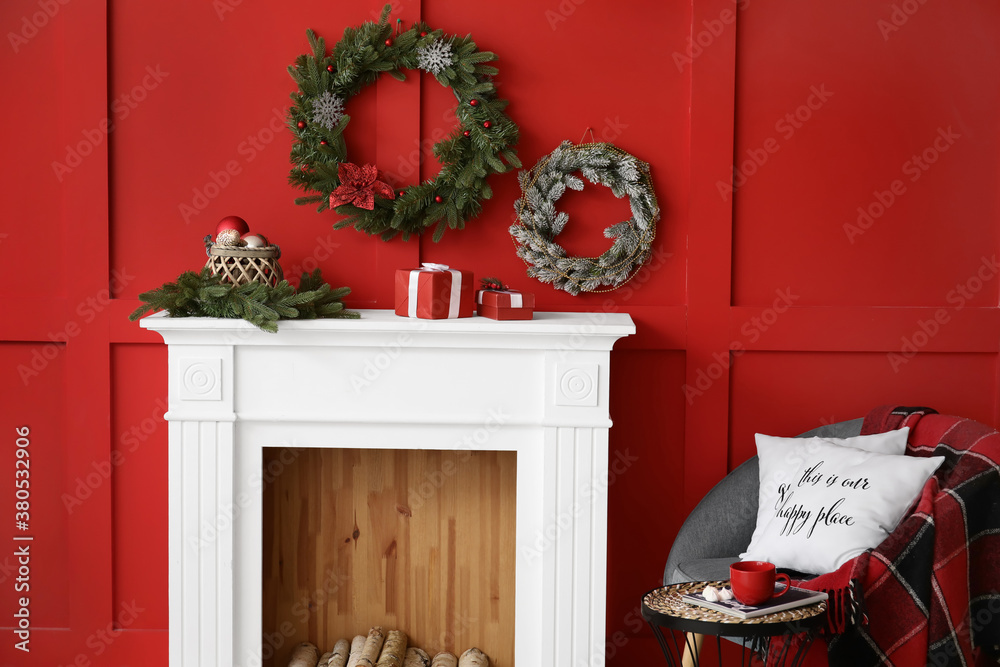 Beautiful Christmas wreaths hanging on wall near fireplace in room