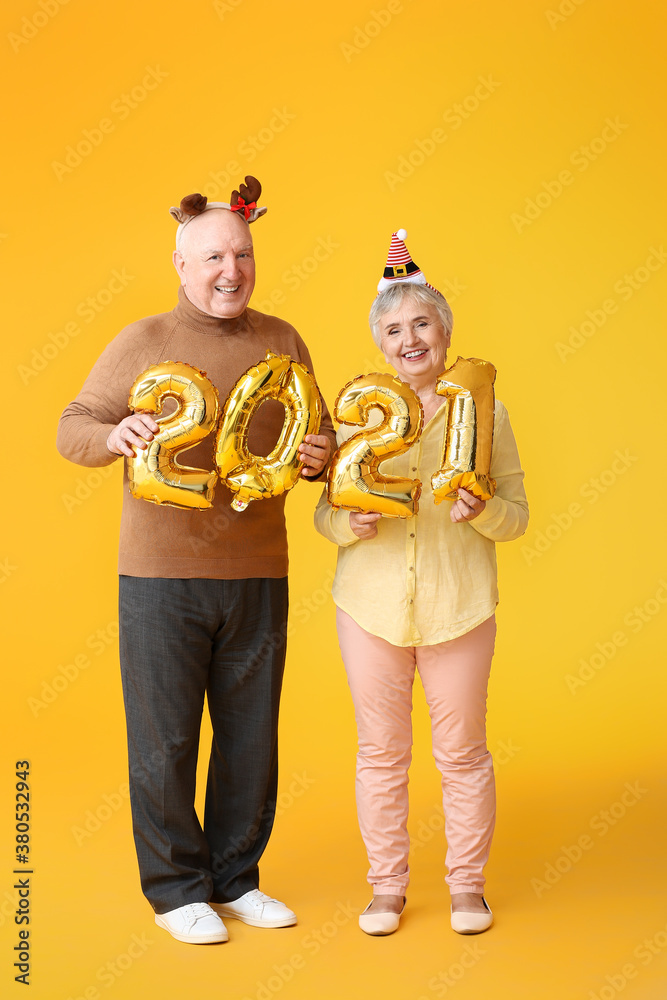 Elderly couple with figure 2021 on color background. New Year celebration