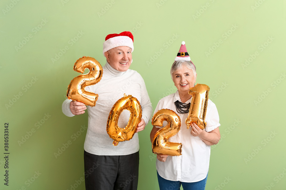 Elderly couple with figure 2021 on color background. New Year celebration