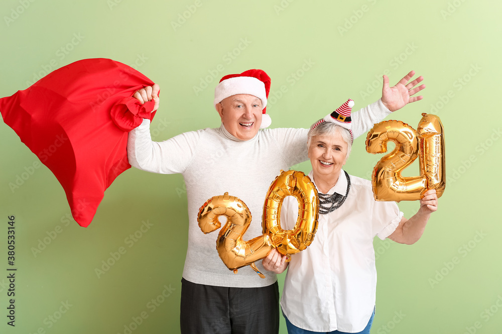 Elderly couple with figure 2021 on color background. New Year celebration