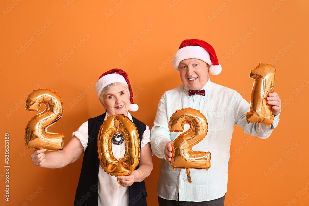 Elderly couple with figure 2021 on color background. New Year celebration