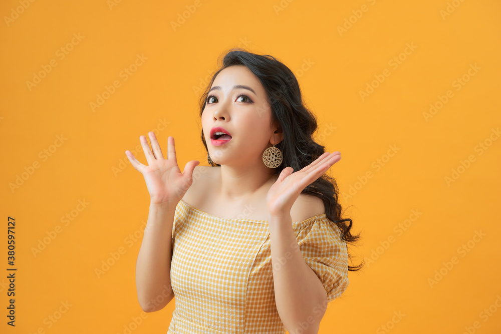 Surprised young woman shouting over yellow background. Looking at camera