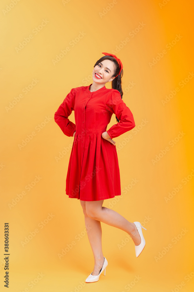 Full length of happy attractive young Asian woman feeling free when standing over orange background.