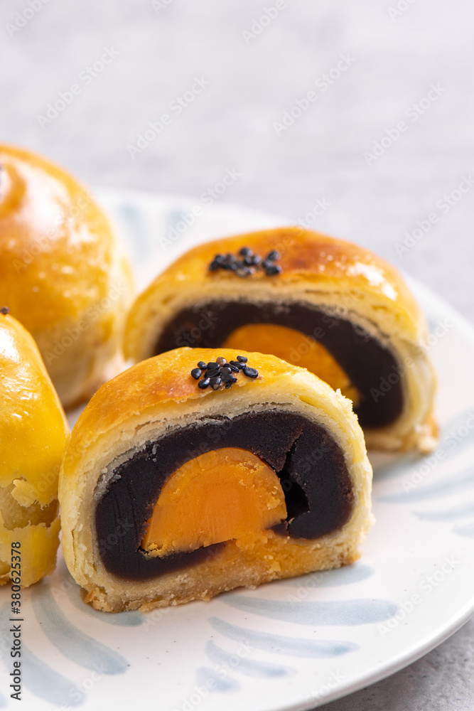 Tasty baked egg yolk pastry moon cake for Mid-Autumn Festival on bright cement table background. Chi