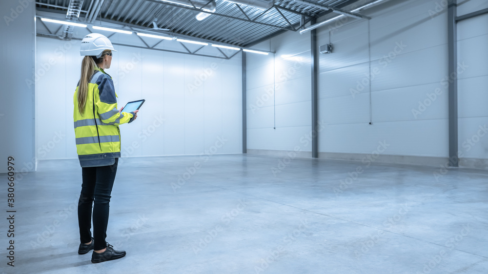 Industry 4.0 Modern Warehouse: Female Engineer in Empty Warehouse Uses Digital Tablet Computer with 