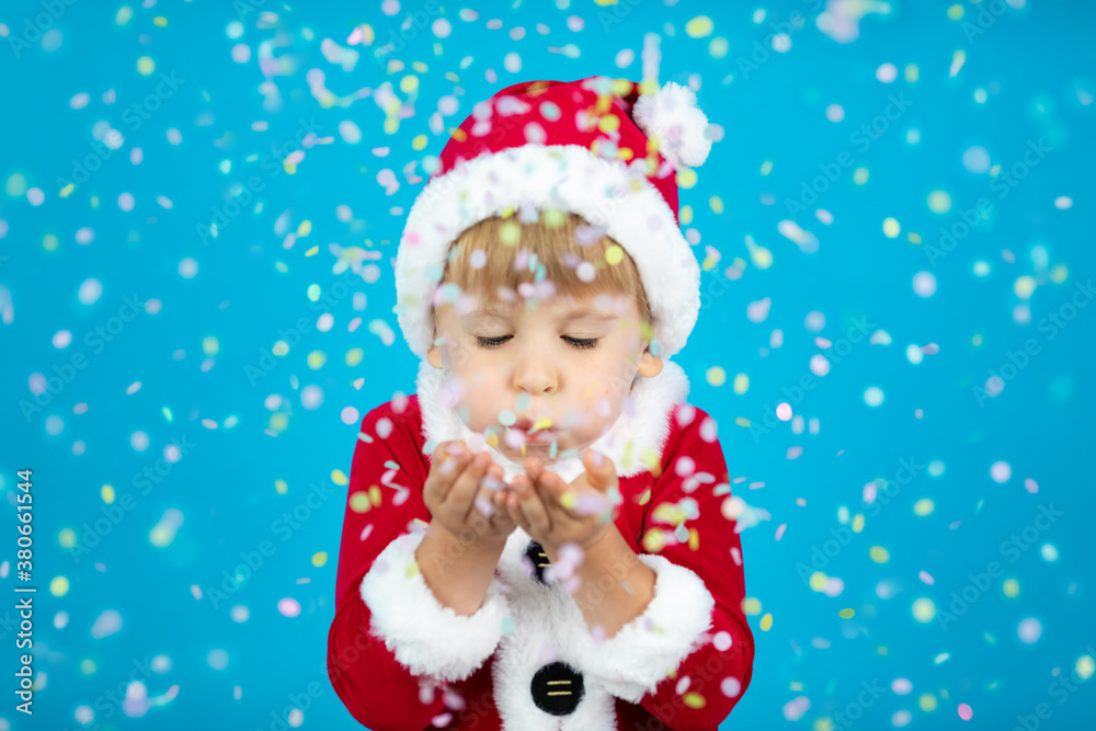 Happy child blowing confetti against Christmas blue background