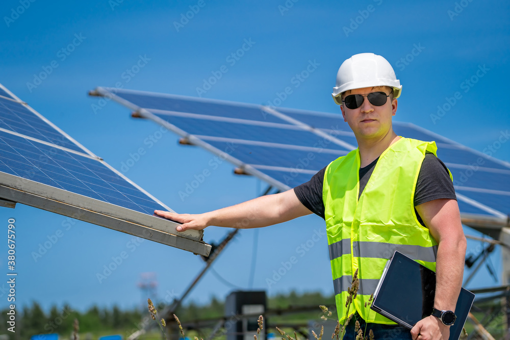 Engineer in worker helmet on solar panels background. Solar power panel. Green energy. Electricity. 