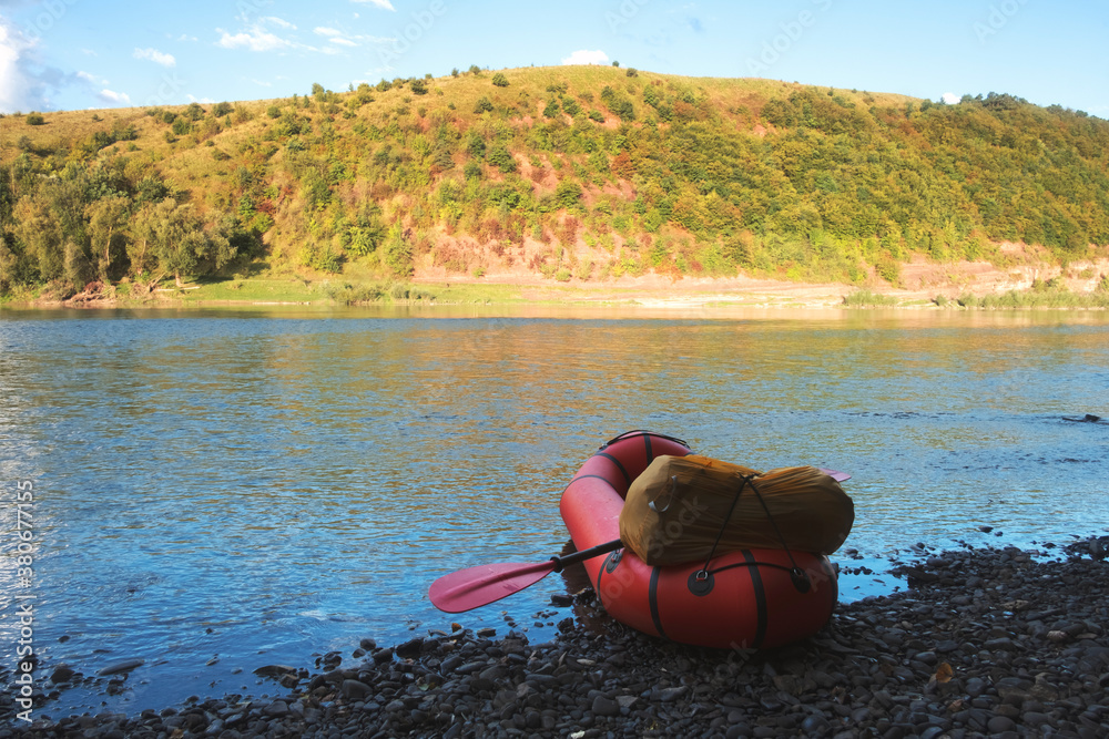 Orange packraft rubber boat with backpack on a river. Packrafting. Active lifestile concept