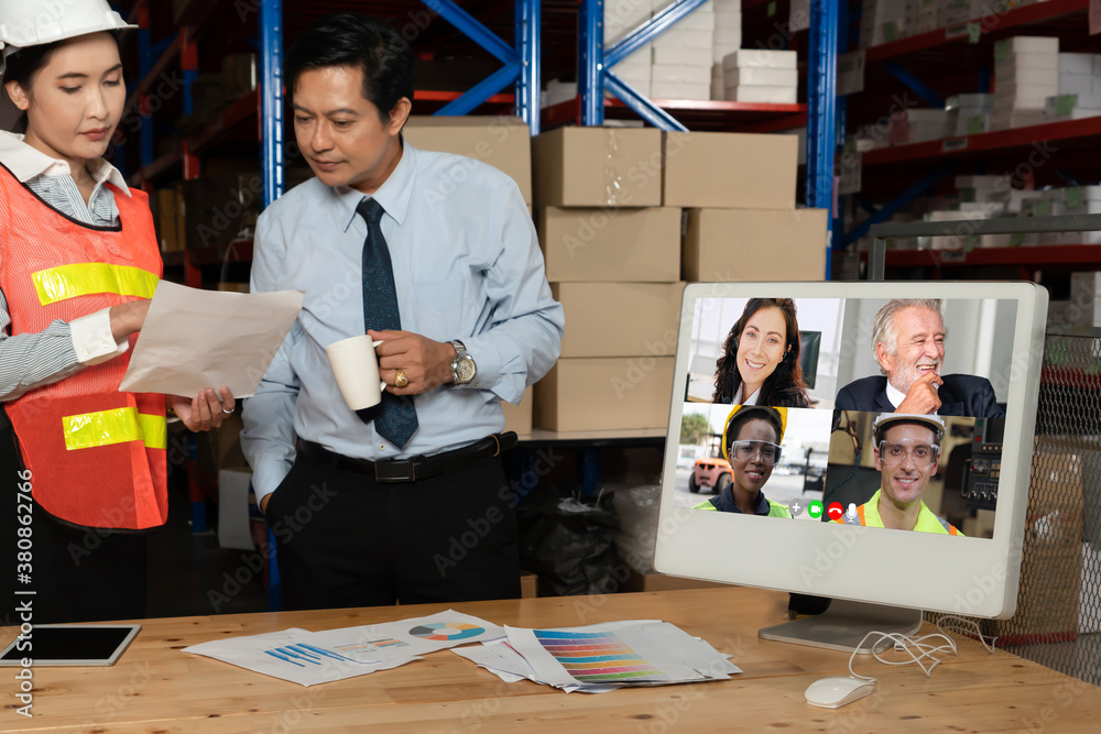 Warehouse staff talking on video call at computer screen in storage warehouse . Online software tech