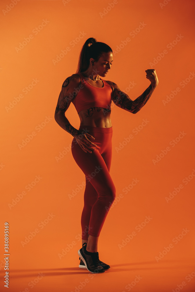 Woman bodybuilder looking at her biceps