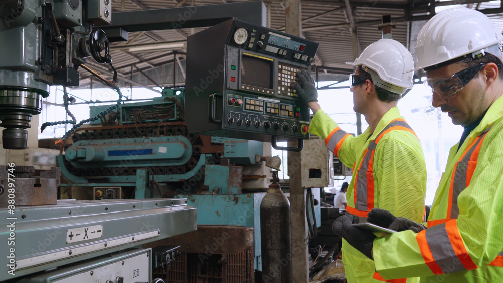 Group of factory workers using machine equipment in factory workshop . Industry and engineering conc