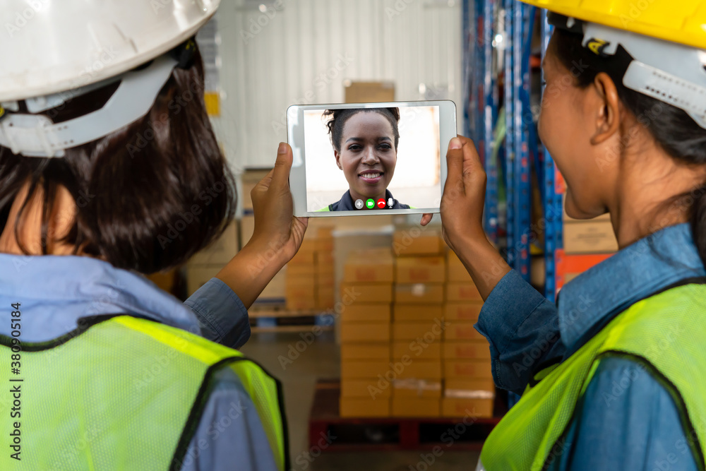 Warehouse staff talking on video call at computer screen in storage warehouse . Online software tech