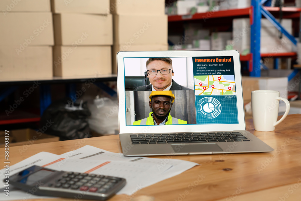 Warehouse staff talking on video call at computer screen in storage warehouse . Online software tech