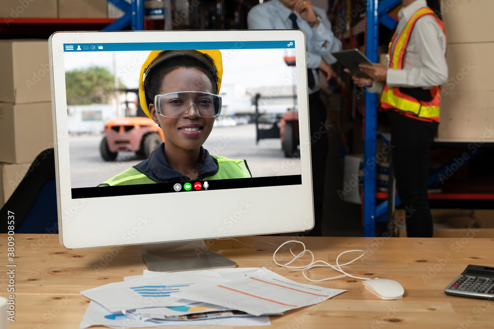 Warehouse staff talking on video call at computer screen in storage warehouse . Online software tech