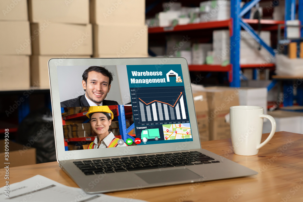 Warehouse staff talking on video call at computer screen in storage warehouse . Online software tech