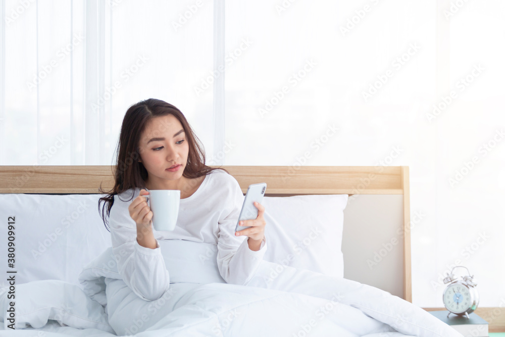 Morning girl with cup of coffee in hands in bed on a white blanket, simple, home, while playing with