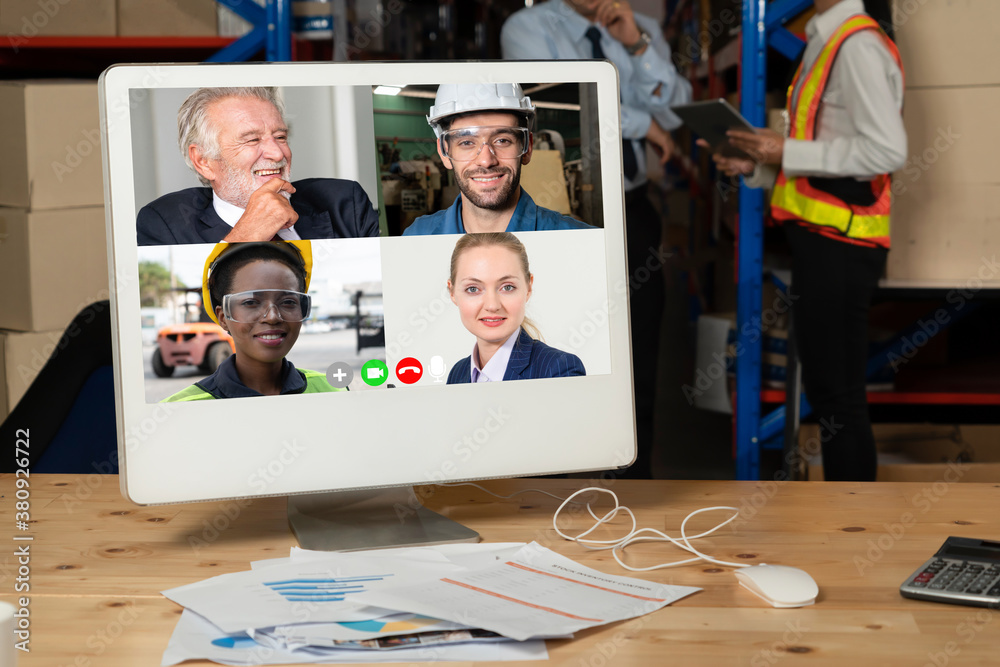 Warehouse staff talking on video call at computer screen in storage warehouse . Online software tech