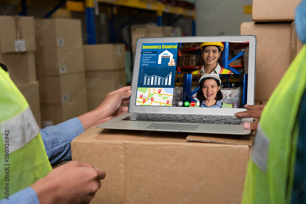 Warehouse staff talking on video call at computer screen in storage warehouse . Online software tech