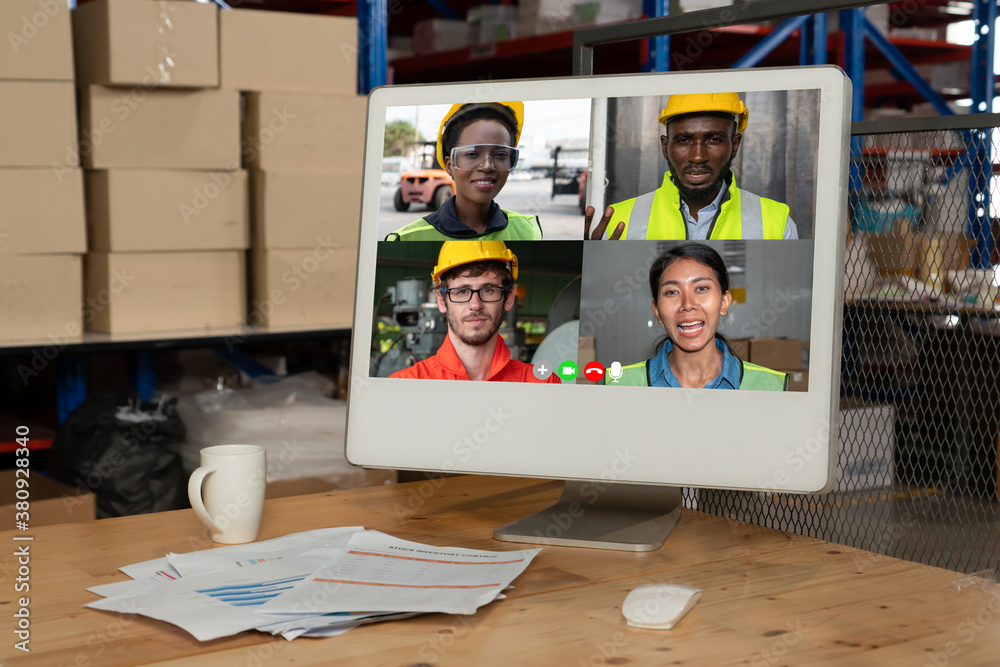 Warehouse staff talking on video call at computer screen in storage warehouse . Online software tech