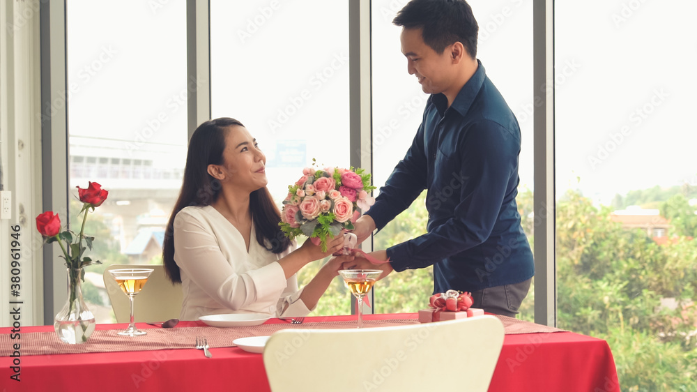 Romantic couple giving gift to lover at restaurant . Happy couple lifestyle .