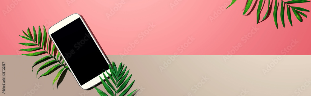 Smartphone with tropical palm leaves - flat lay