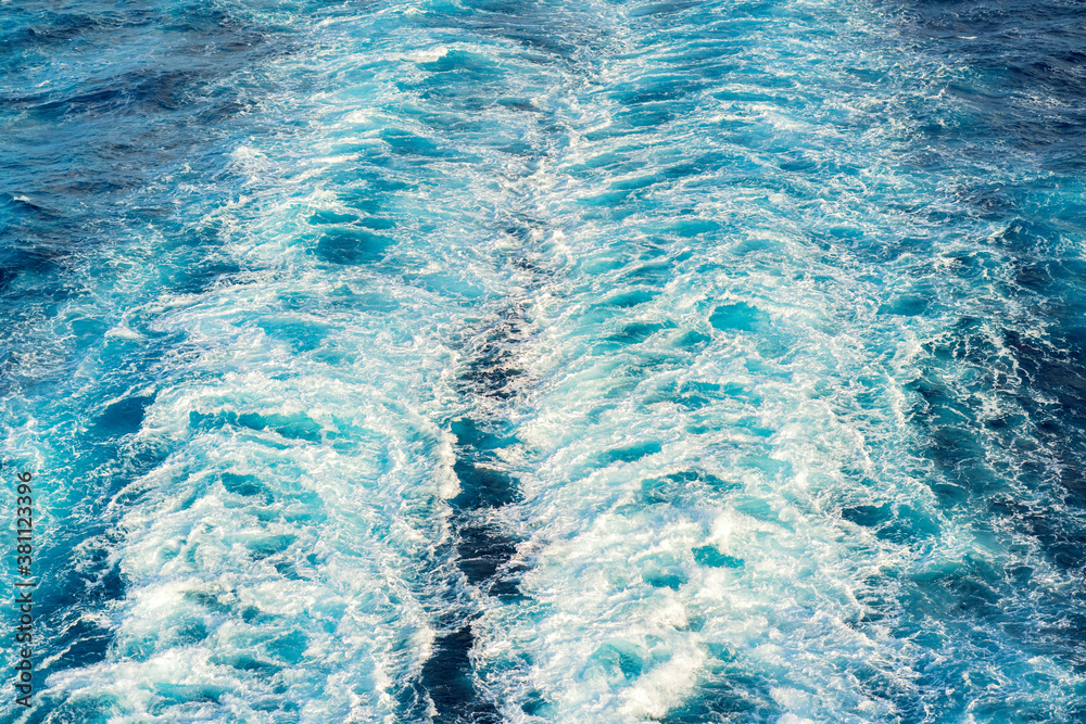 Atlantic ocean with blue water on a sunny day. Waves, foam and wake caused by cruise ship in the sea