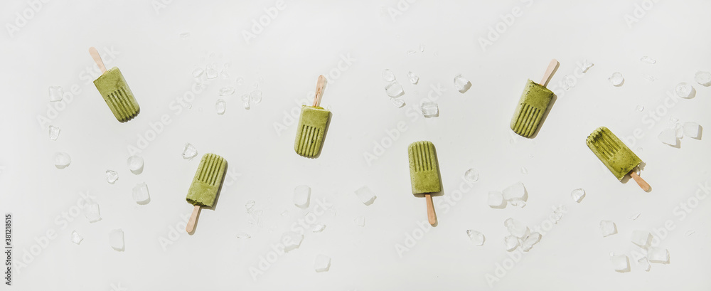 Green matcha coconut vegan ice cream popsicles. Flat-lay of matcha popsicles over white table backgr