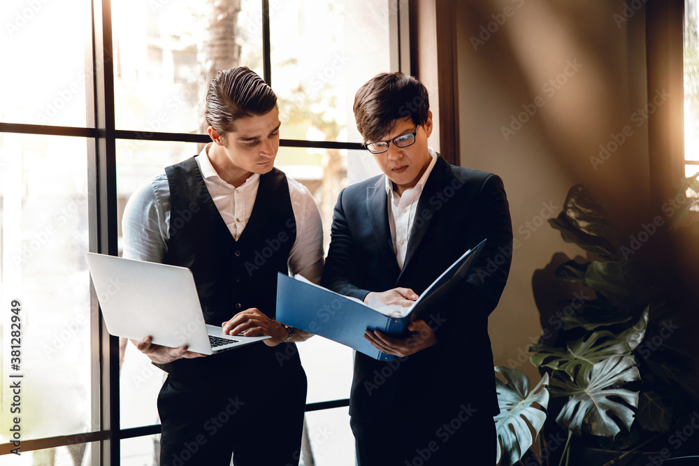 Two Businessman Working Together on Computer Laptop in Creative Workplace.