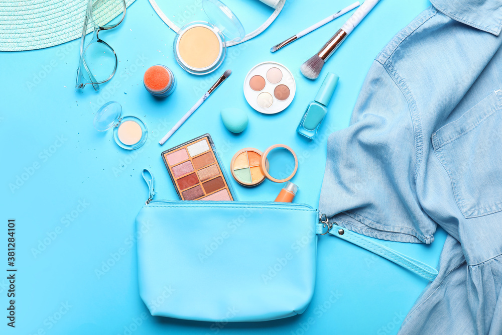 Makeup bag with decorative cosmetics, clothes and accessories on color background