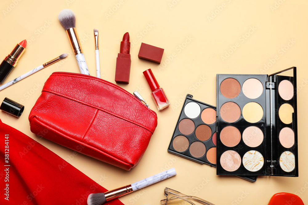 Makeup bag with decorative cosmetics, clothes and accessories on color background