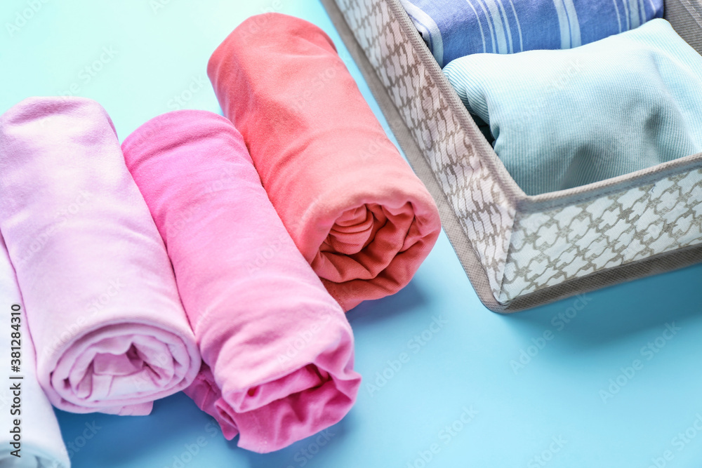 Organizer with clean clothes on color background