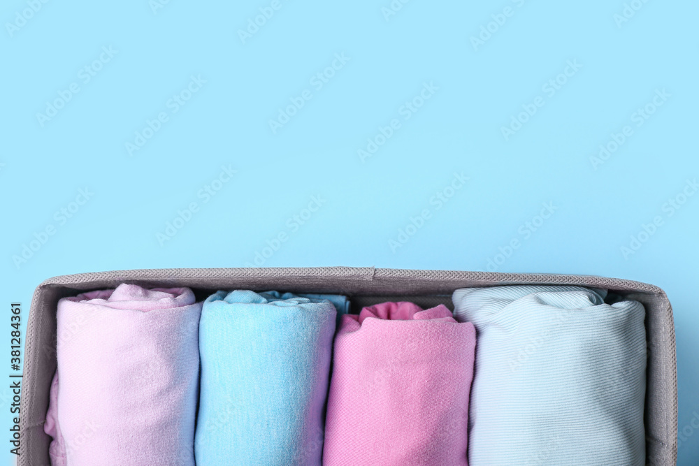 Organizer with clean clothes on color background