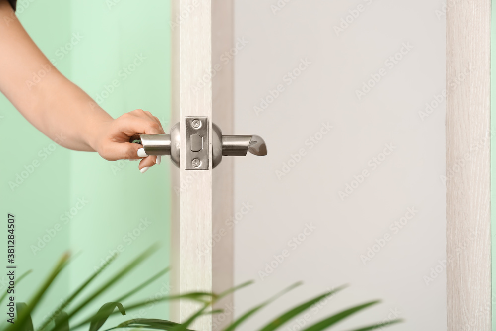 Woman opening door indoors, closeup