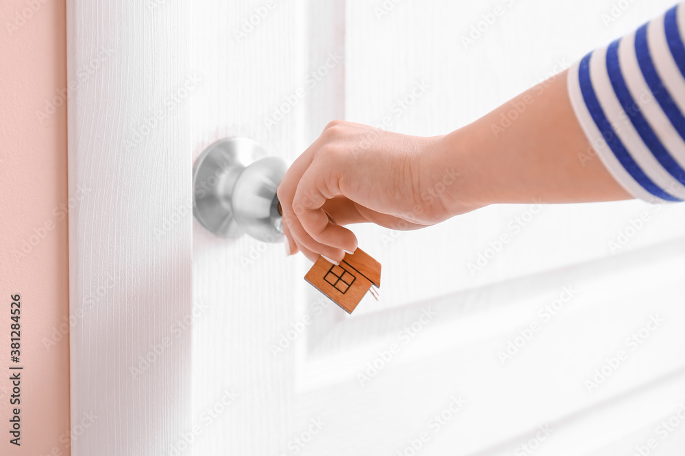 Woman using key to open door indoors