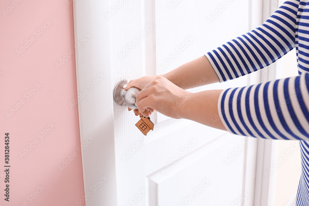 Woman using key to open door indoors