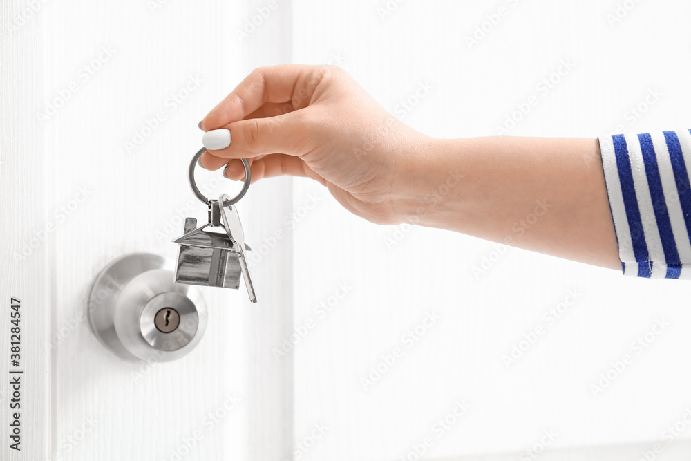 Woman with key from house near door indoors