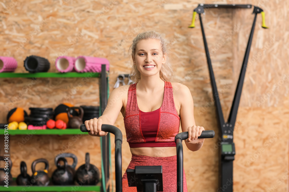 Young woman training on exercising bike in gym