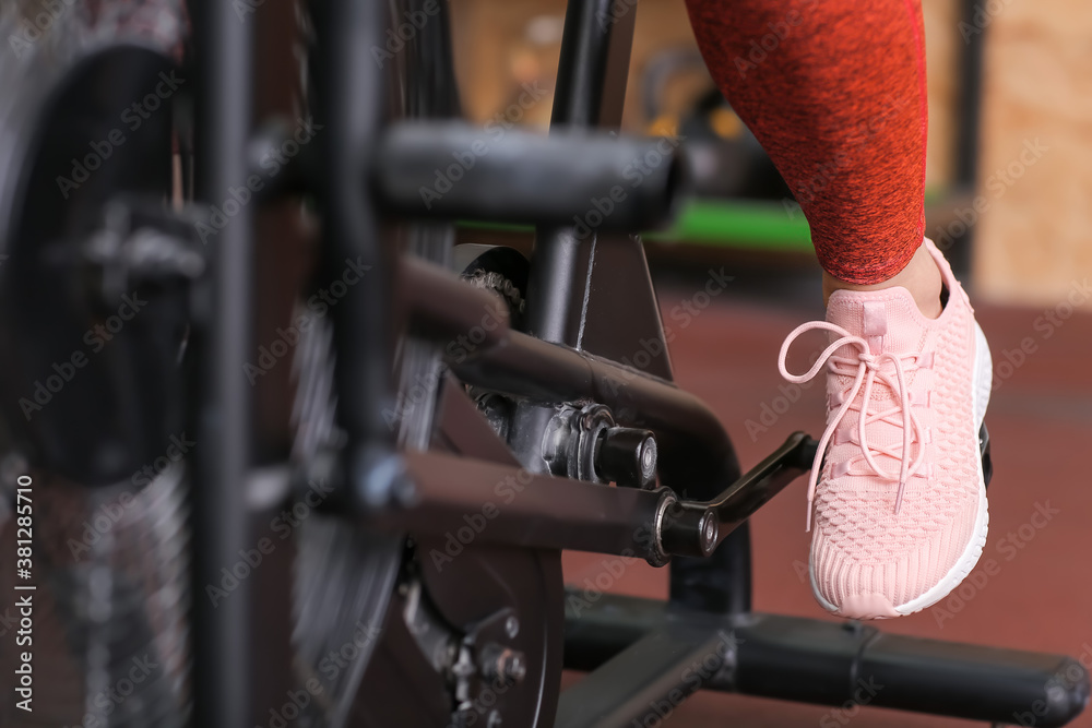 Young woman training on exercising bike in gym, closeup