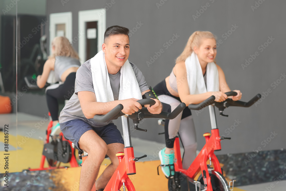 Young people training on exercising bike in gym