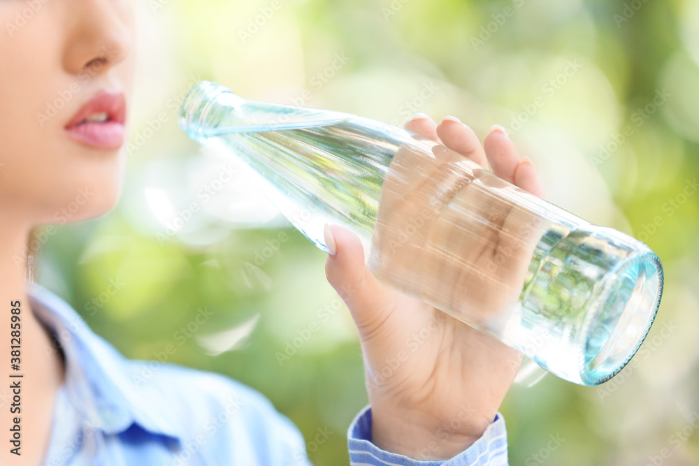 Woman with bottle of water outdoors, closeup